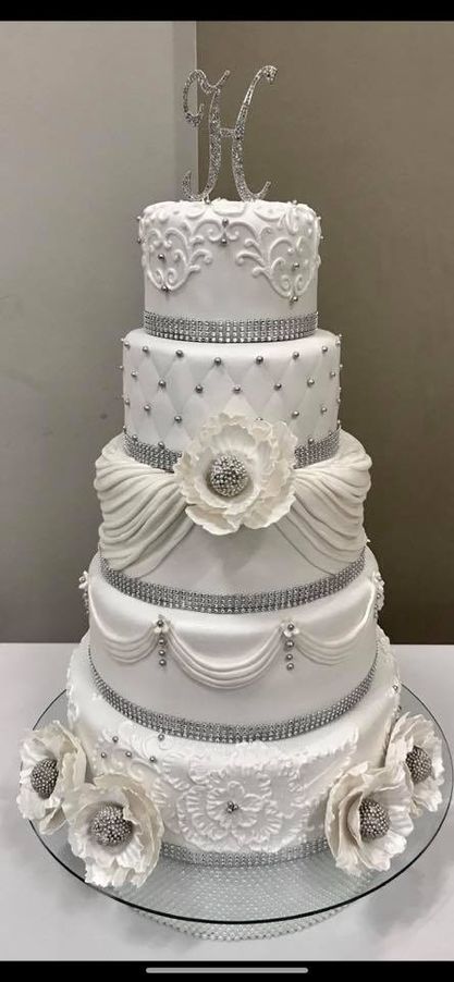 five tier wedding cake with intricate icing, flowers, and silver details