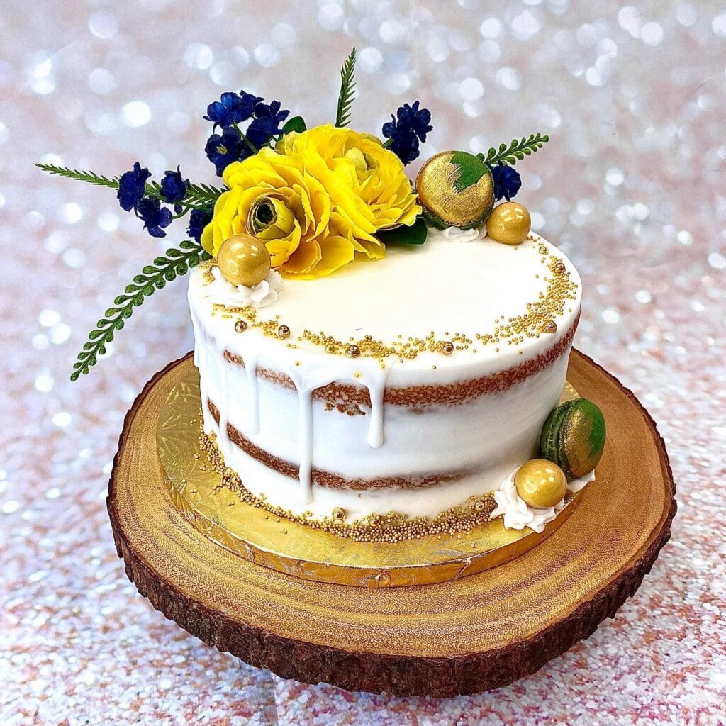 279891681_10159645129130306_8878696220681170040_n rough iced cake with pink and blue flowers
