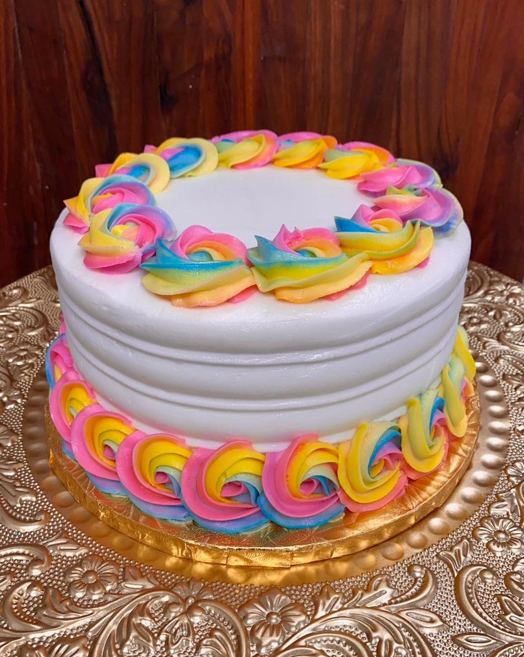 white cake with rainbow rosettes