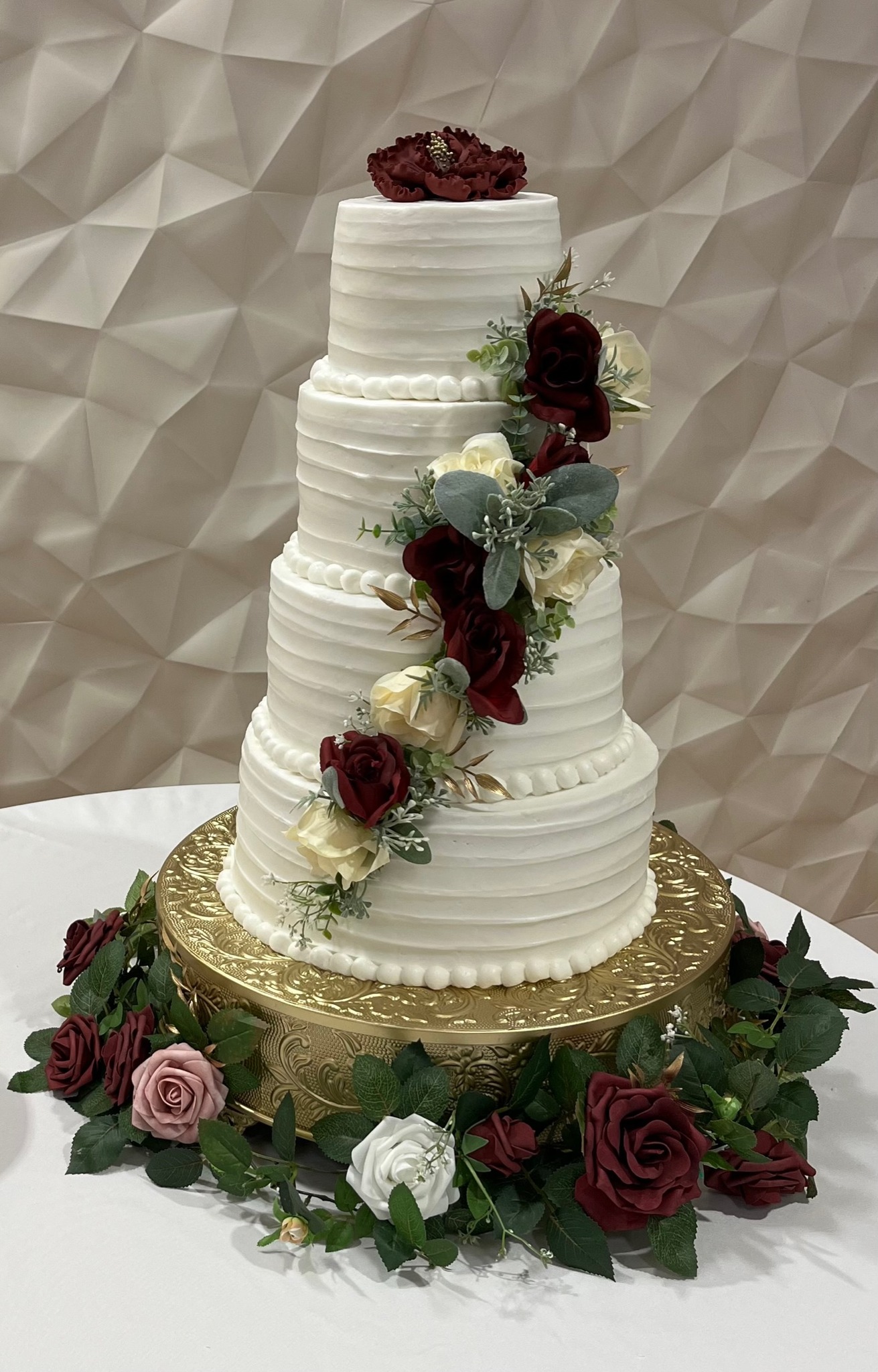 four tier wedding cake with cascading red roses